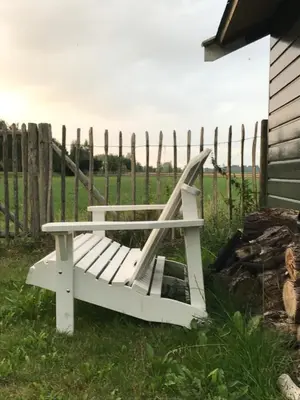 a white bench sitting in the grass next to a fence at Nabij de Molen in Wijdenes