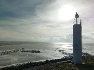 a lighthouse sitting on the side of the ocean at Nabij de Molen in Wijdenes