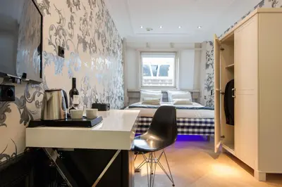 a room with a bed and a kitchen with a desk at Amsterdam Canal Hotel in Amsterdam
