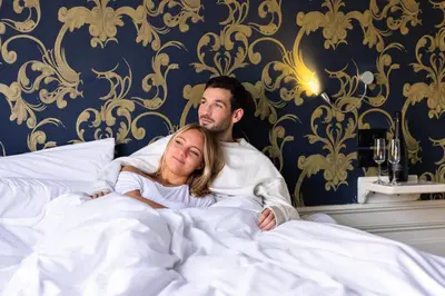 a man and a woman laying in bed at Amsterdam Canal Hotel in Amsterdam
