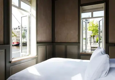 a bedroom with a white bed and two windows at SWEETS - Amstelschutsluis in Amsterdam