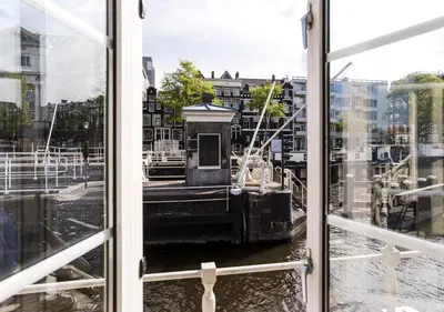 a boat in the water through a window at SWEETS - Amstelschutsluis in Amsterdam