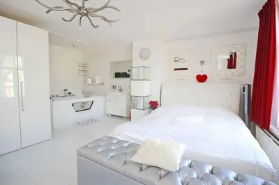 a white bedroom with a large bed and a bathroom at White Luxury Penthouse in City Centre in Amsterdam