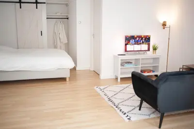 a bedroom with a bed and a couch and a television at Achter de duinen in Zandvoort