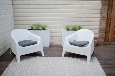two white chairs on a porch with plants at Achter de duinen in Zandvoort
