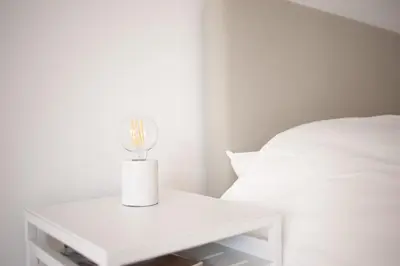 a white table with a candle on it next to a bed at Achter de duinen in Zandvoort