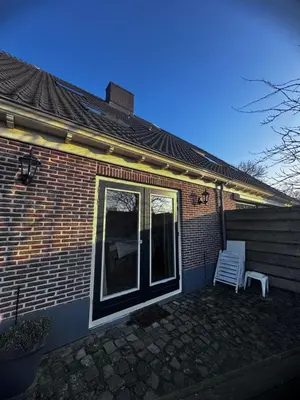 a brick house with a window and a white chair at Ora et Labora in Beets