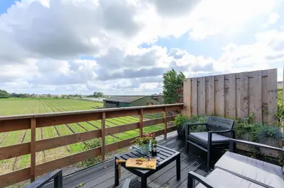a deck with a table and chairs and a fence at B&B Blossom in Lisse