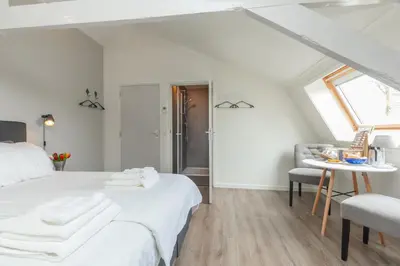 a white bedroom with a bed and a table at B&B Blossom in Lisse