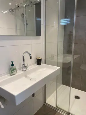 a white bathroom with a sink and a shower at Amsterdam Beach Home 46 in Zandvoort