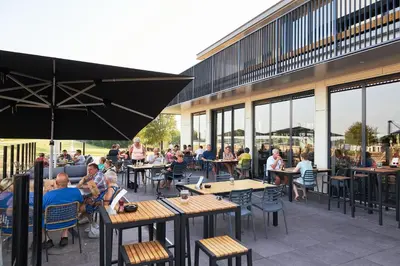 a group of people sitting at tables outside a building at RCN Zeewolde in Zeewolde