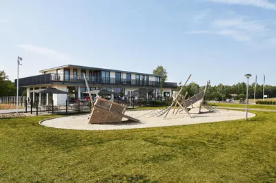 a playground with two swings in front of a building at RCN Zeewolde in Zeewolde