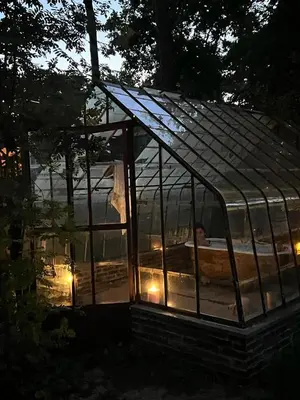 a glass greenhouse with a person in it at night at Villa in the forest near the beach in Bergen
