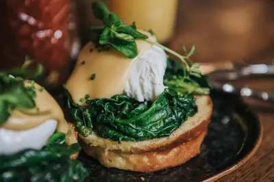 a sandwich with greens on top of it on a plate at Hotel V Nesplein in Amsterdam
