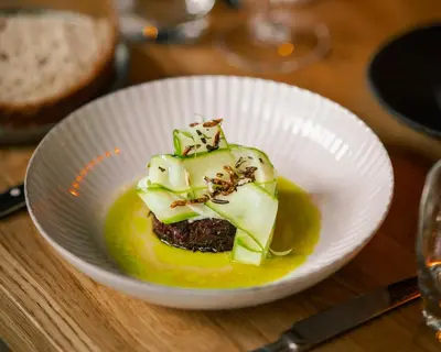 a white bowl of food on a wooden table at Hotel V Nesplein in Amsterdam