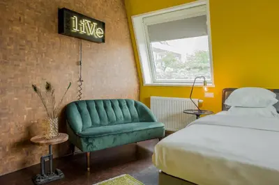 a bedroom with a green chair and a bed at Hotel V Nesplein in Amsterdam