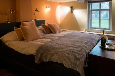 a bed with pillows on it in a room with a window at De Buren in Vleuten