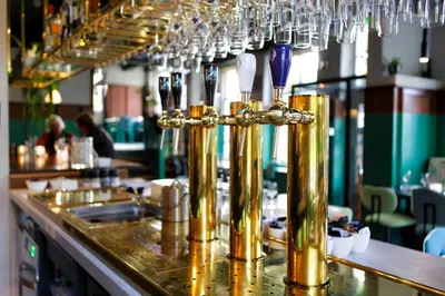 a bar with gold pipes and wine glasses at De Buren in Vleuten