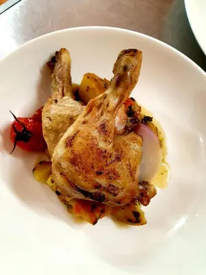 a white plate with chicken and vegetables on a table at De Buren in Vleuten