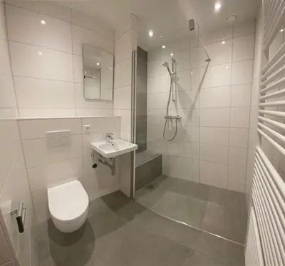 a white bathroom with a toilet and a sink at Appartementen Zeezicht - 1 in Katwijk aan Zee