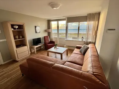a living room with a brown couch and a table at Appartementen Zeezicht - 1 in Katwijk aan Zee