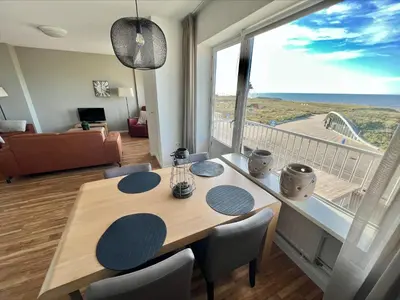 a dining room with a table and a large window at Appartementen Zeezicht - 3 in Katwijk aan Zee