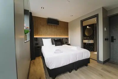 a bedroom with a large bed with white sheets at Hotel Bell in Zandvoort