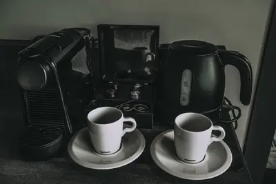 two cups on plates next to a coffee maker at Hotel Bell in Zandvoort