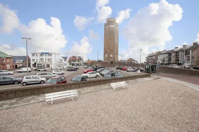 a parking lot with parked cars and a clock tower at Hotel Bell in Zandvoort