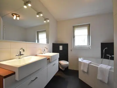 a bathroom with two sinks and a tub and a toilet at Family Home in Zeewolde by Forest Trails in Zeewolde