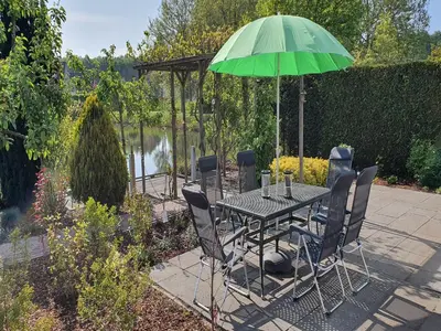 a table and chairs with a green umbrella at Family Home in Zeewolde by Forest Trails in Zeewolde
