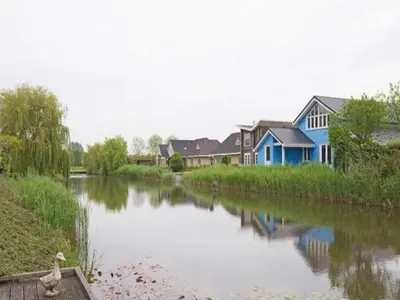 a blue house on the side of a river at Family Home in Zeewolde by Forest Trails in Zeewolde