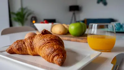 a plate with a croissant and a glass of orange juice at Appartementen De Boulevard in Zandvoort