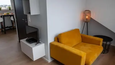a living room with a yellow chair and a tv at Appartementen De Boulevard in Zandvoort