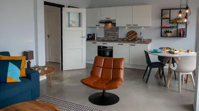 a living room and kitchen with a table and a blue couch at Appartementen De Boulevard in Zandvoort