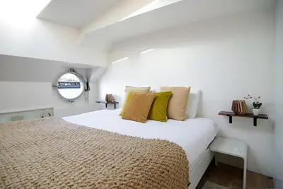 a white bedroom with a large bed with yellow pillows at Eco HouseBoat in Amsterdam