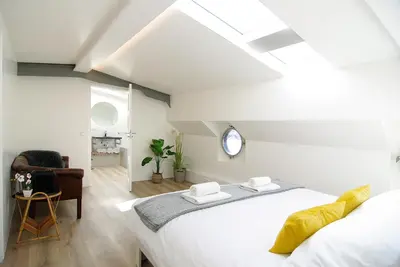 a white bedroom with a bed and a chair at Eco HouseBoat in Amsterdam