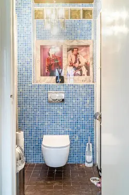 a blue tiled bathroom with a toilet and pictures at BEAUTIFUL APARTMENT WiTH ASIAN STYLE BEDROOM NEAR RAI & CENTER in Amsterdam