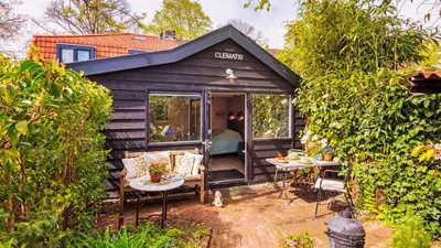 a black tiny house with a patio and a bedroom at Studio Clematis in Bergen