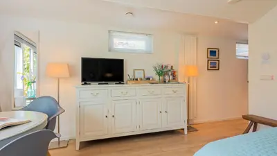 a living room with a tv on a white dresser at Studio Clematis in Bergen
