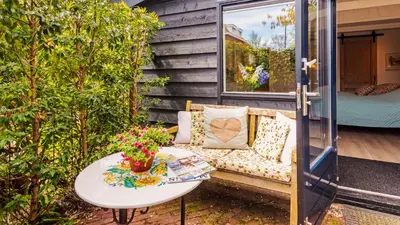 a patio with a couch and a table with flowers at Studio Clematis in Bergen