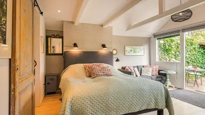 a bedroom with a bed and a couch and a window at Studio Clematis in Bergen