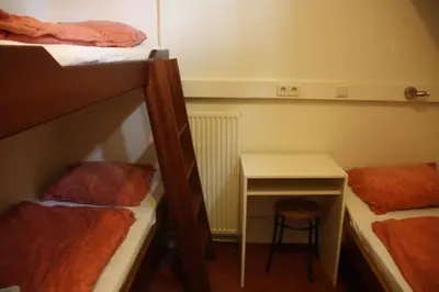 a small room with two bunk beds and a desk at Hotelschip Gandalf in Amsterdam