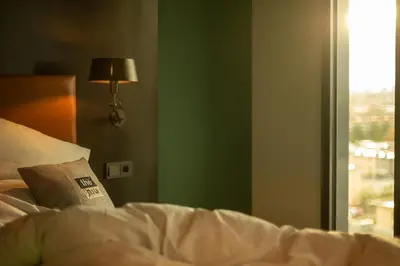 a bed with a pillow and a lamp and a window at Holiday Inn - the niu, Fender Amsterdam in Amsterdam