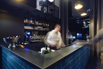 a man standing behind a bar in a restaurant at Holiday Inn - the niu, Fender Amsterdam in Amsterdam