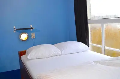 a blue bedroom with two beds and a window at Flying Pig Uptown in Amsterdam