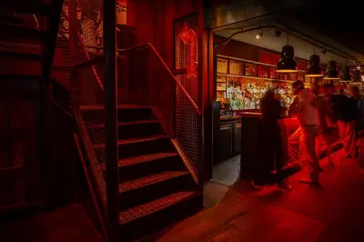 a staircase in a bar with people standing at a bar at St Christopher's Inn Amsterdam - The Winston in Amsterdam