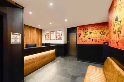 a restaurant with a bar with an orange wall at St Christopher's Inn Amsterdam - The Winston in Amsterdam