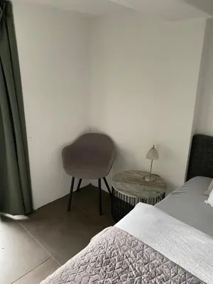 a bedroom with a bed and a chair and a table at Zomerhuis Wonders in Zandvoort