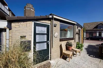 a small building with a door and a chair at Zomerhuis Wonders in Zandvoort